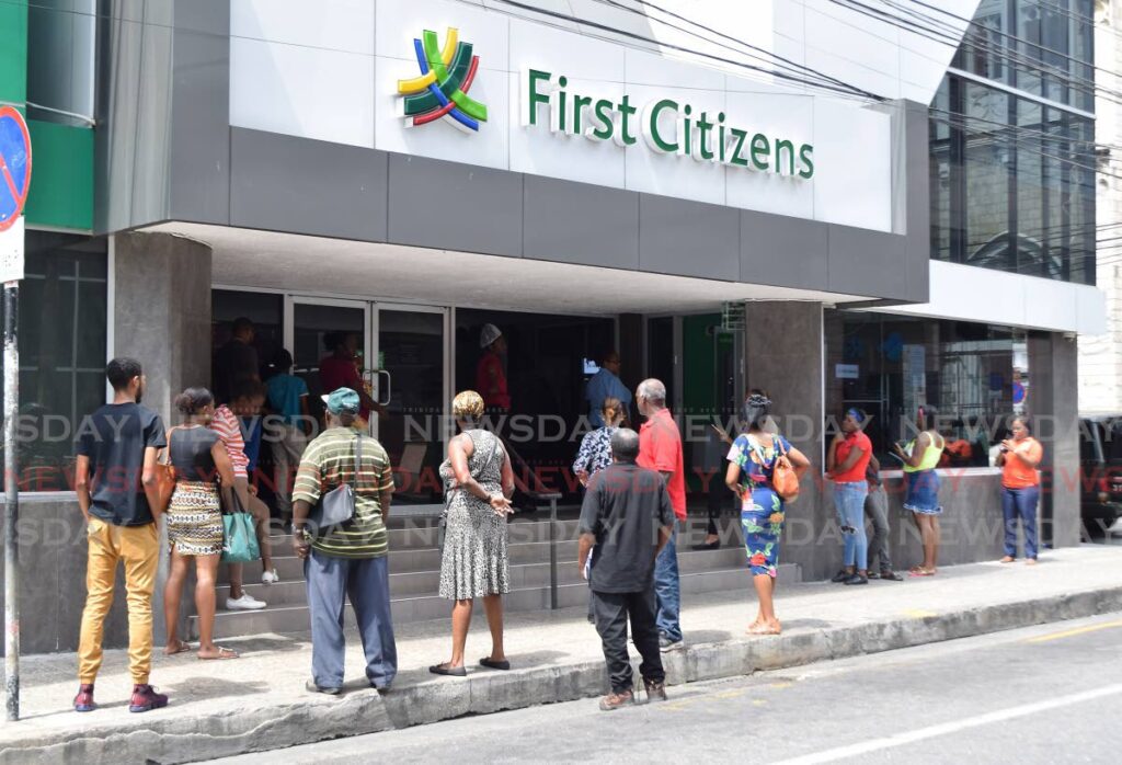 Customers line up outside First Citizens Bank on Park Street, Port of Spain. - File photo