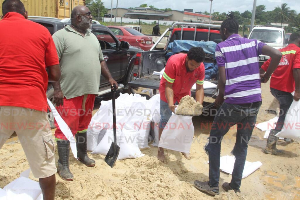 Sangre Grande Regional Corporation employees and volunteers, fill sandbags at their Turure stockpile in preparation for the storm on Tuesday. Photo by Angelo Marcelle