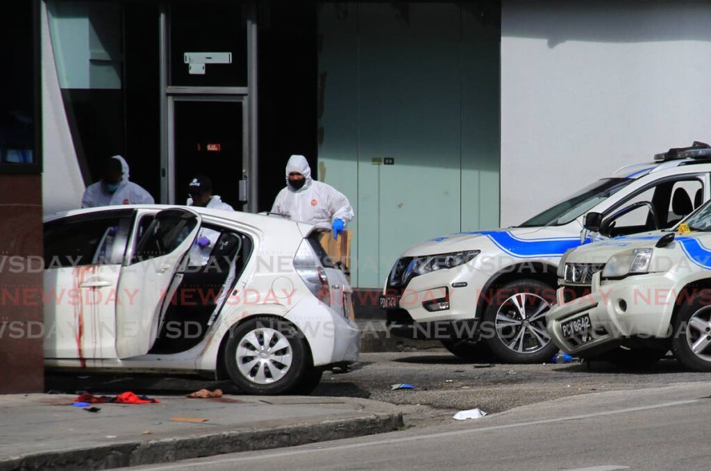 Crime scene investigators examine the car in which four men died after a shootout with police at the corner of Chacon Street and Independence Square, Port of Spain on Saturday. - SUREASH CHOLAI