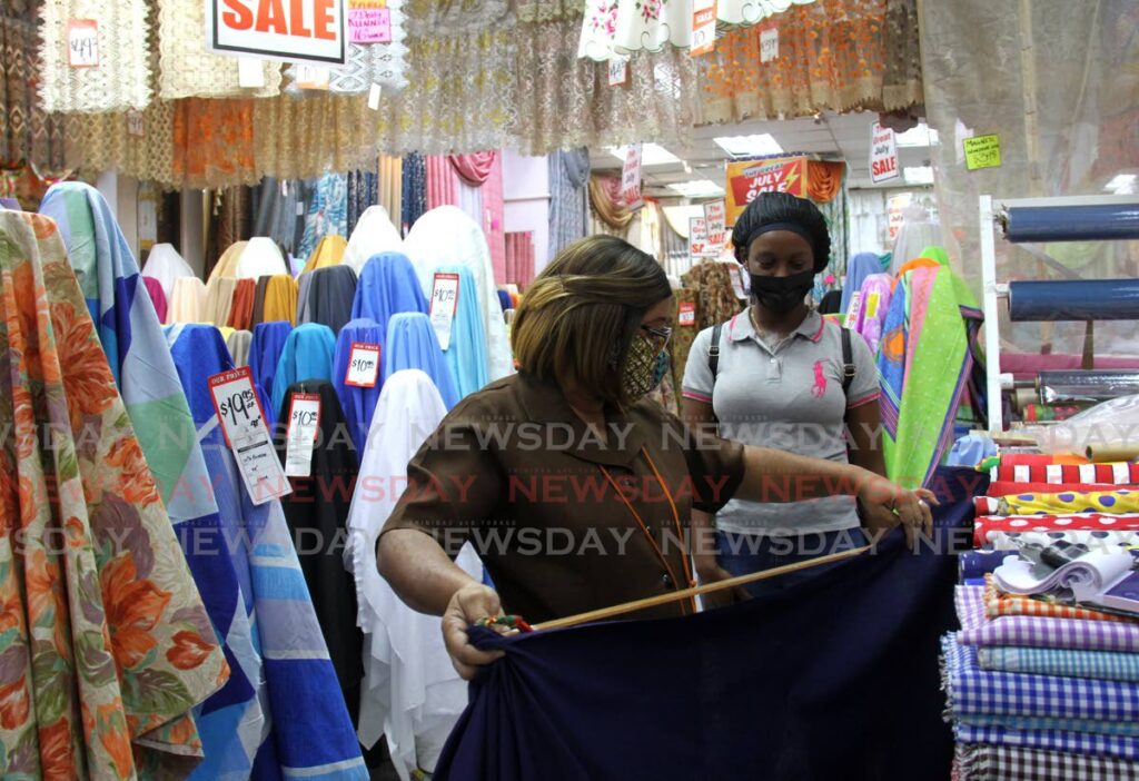 Alice Ramcharan measures a piece of fabric for customer Aaliyah Ross at Jimmy Aboud - The Textile King on Queen Janelle Commissiong Street in Port of Spain on Tuesday. - PHOTO BY AYANNA KINSALE