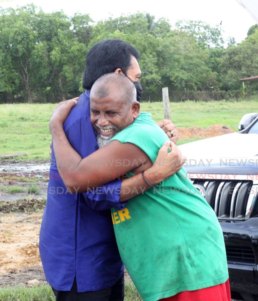 Shiraz Khan, president of the Trinidad Unified Farmers Association, hugs Agriculture Minister Kazim Hosein at Khan's farm in Carlsen Field on Saturday. - ROGER JACOB