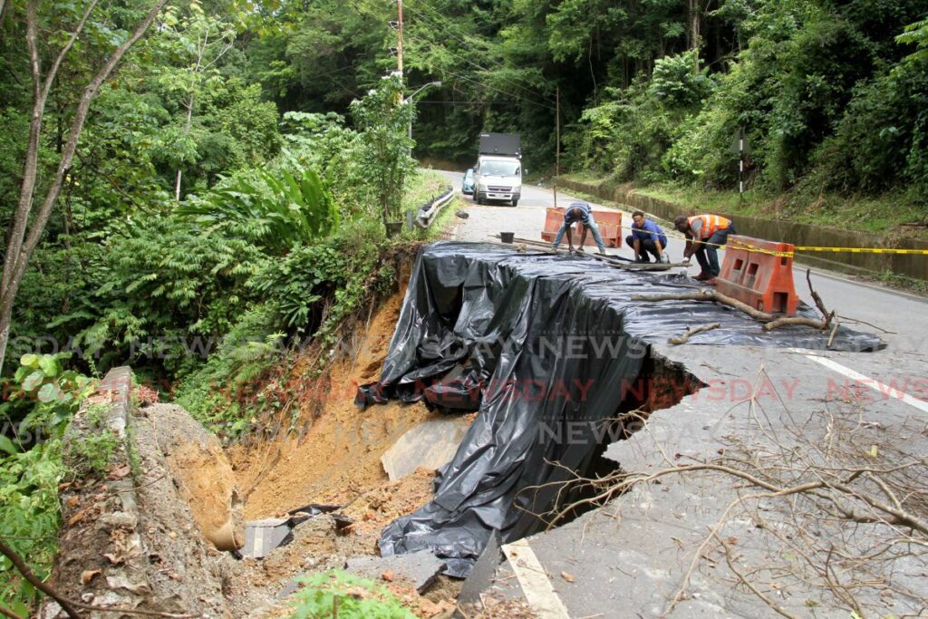 Ministry of Works and Transport, Highway Division workers use plastic to cover the area where the landslip took place to prevent any more damage to the North Coast Road on Saturday. - AYANNA KINSALE