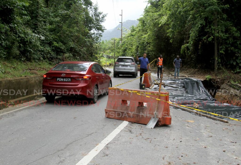 A driver cautiously goes around safety barriers along the broken road.  - AYANNA KINSALE