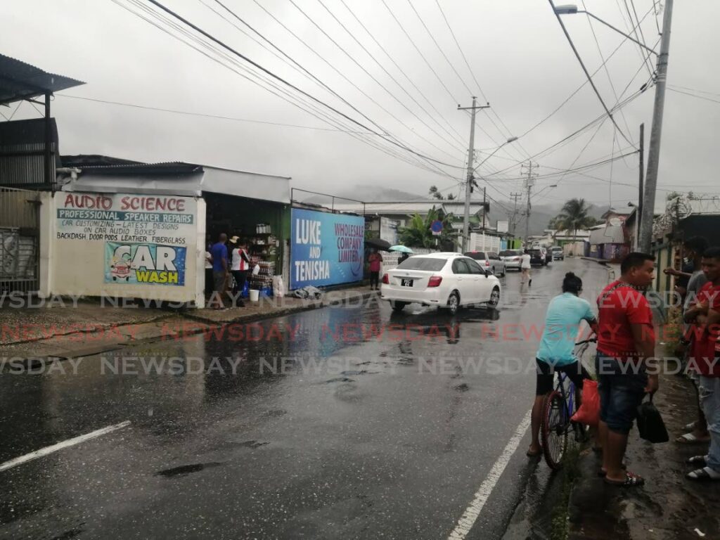 Luke Dalipsingh's employees gather opposite his business on Quesnel Street, Arima, shortly after his body was removed. - Jensen La Vende