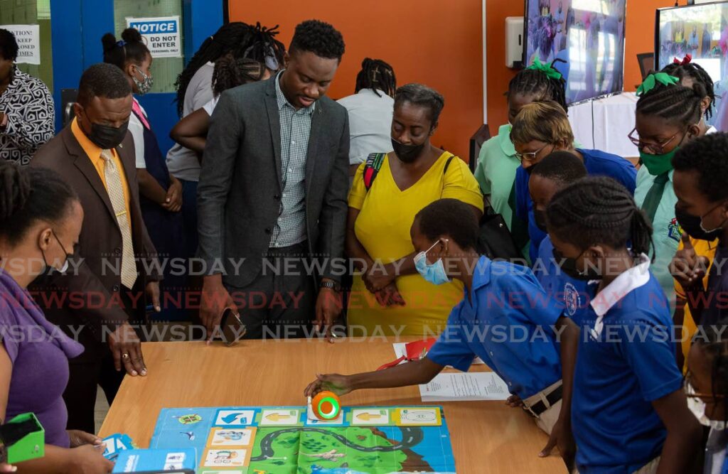 Students of schools around Tobago learn the basics of computer coding and programing, on a chart using a mouse, while Chief Secretary Farley Augustine seems also intrigued at Digicel Foundation and We Code Caribbean's launch of the five-week programme at Tobago Information Technology Ltd, at Signal Hill on Monday. Photo by David Reid
