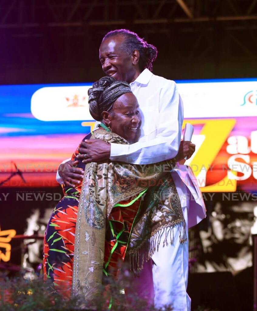 Calypso legend David Rudder gets a hug from Eintou Pearl Springer after she presented him with the Shikamoo (praise to elder) award for his contribution to the calypso artform through the years at his concert at the the Lidj Yasu Omowale Emancipation Village at the Queen’s Park Savannah on Friday night.    Photo by Sureash Cholai
