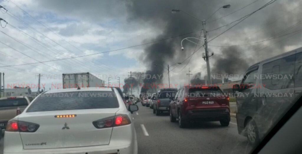 Fires burn along the Beetham Highway on Monday morning after police thwarted an attempt by residents to stage a fiery protest over the police-involved shooting deaths of three men in Port of Spain on the weekend. Photo by Elizabeth Gonzales.