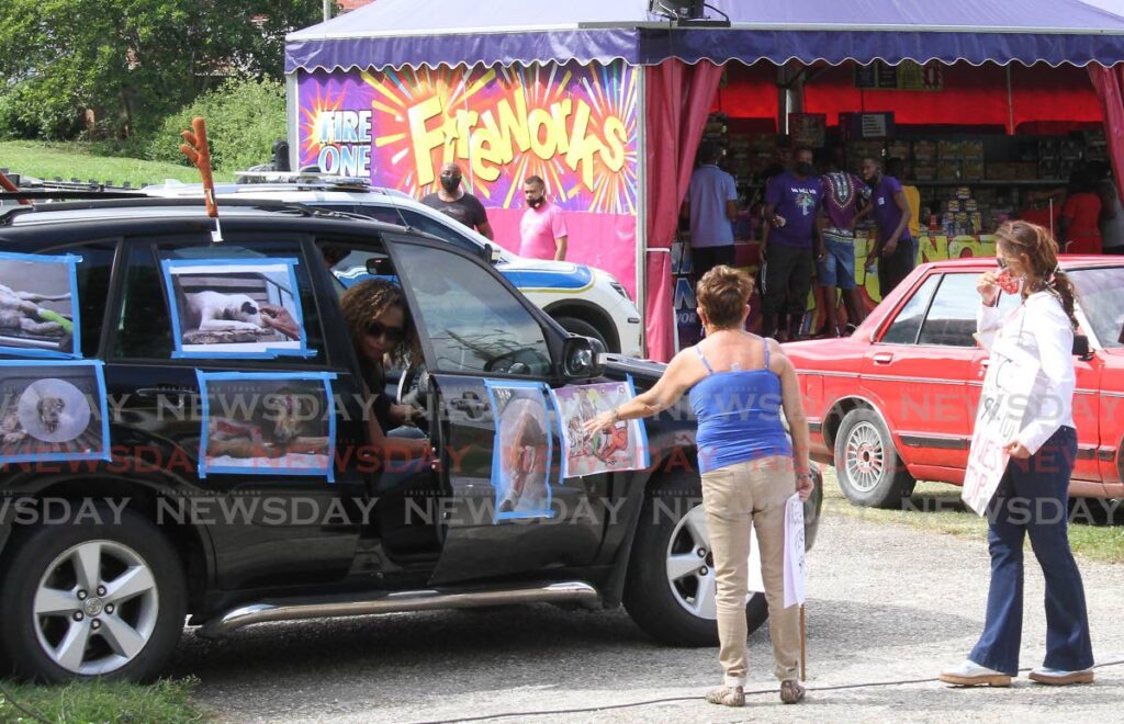 A woman parks her vehicle covered with posters of wounded animals to join animal rights activist Nalini Dial to protest the sale of fireworks at a roadside stall in Maraval on December 31, 2020. - File photo