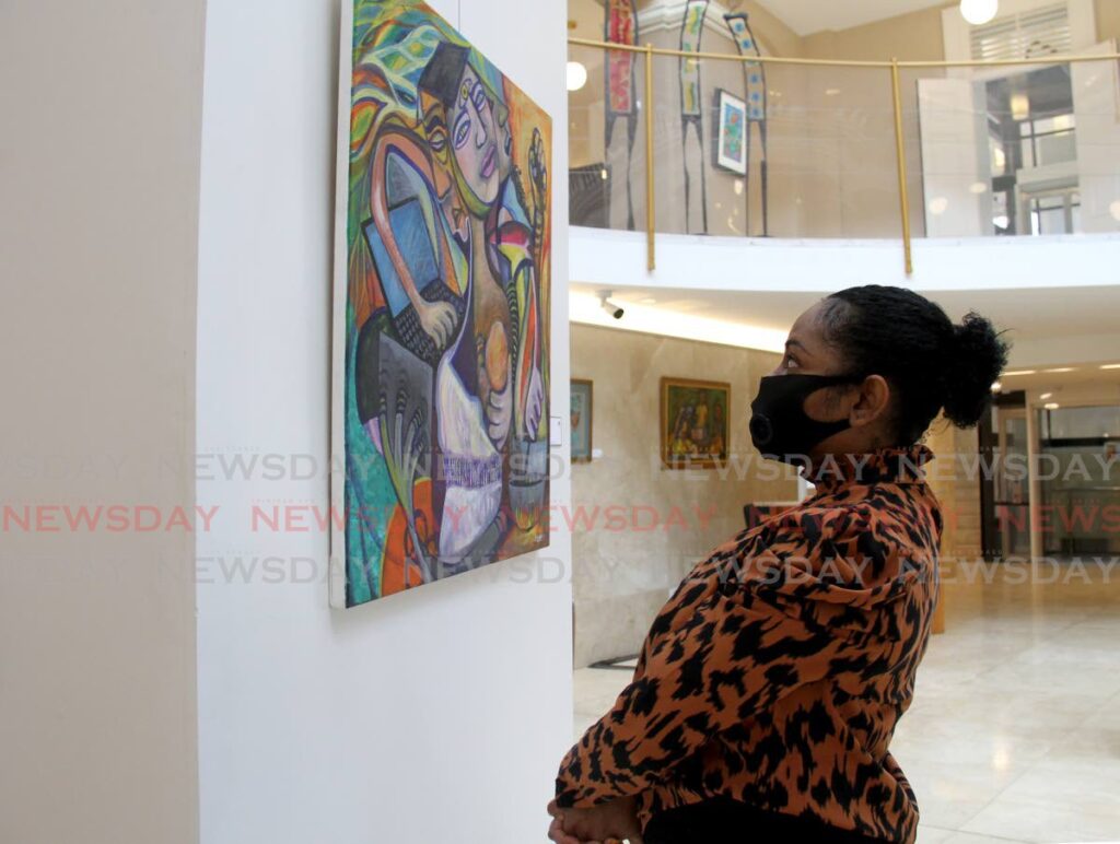 Anthea Grant looks at an acrylic on canvas art piece, Supergirl, at the Rotunda Gallery, Red House in March 2021. - AYANNA KINSALE