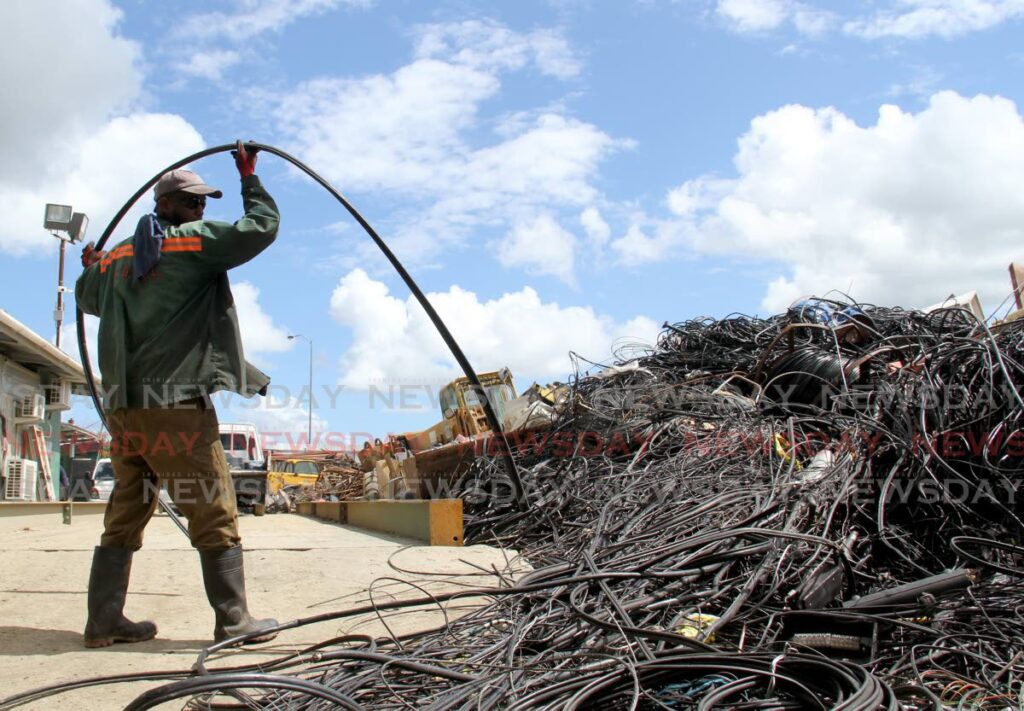 A worker collects a piece of copper wire at the West Indian Salvage and Recycling Company Ltd, Bypass Road, Kelly Village, in November last year.   - FILE PHOTO/AYANNA KINSALE