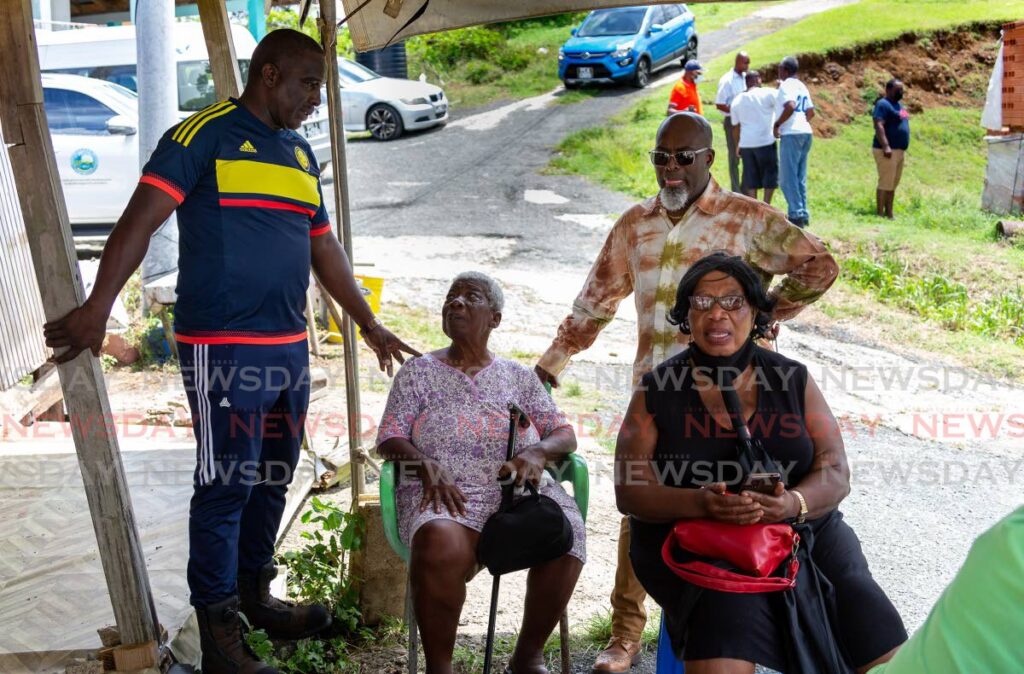 THA secretaries Ian Pollard, left, and Terance Baynes, right, reassure Bethany resident Marjorie Taylor after her house was damaged during the passage of a tropical wave in June. FILE PHOTO/DAVID REID  - 