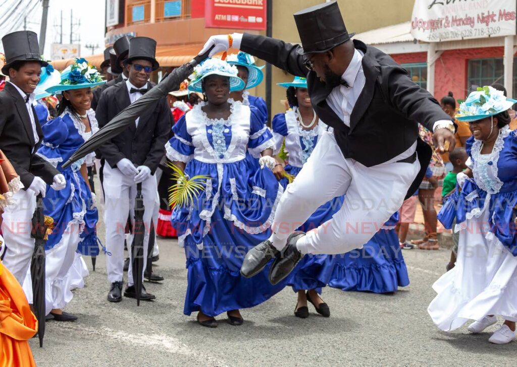 Shumuald Carrington, centre,clicks his heels during a jig for the Moriah Ole Time Wedding segment, at Emancipation Day celebrations, Milford Road, Crown Point, Monday. Photo by David Reid