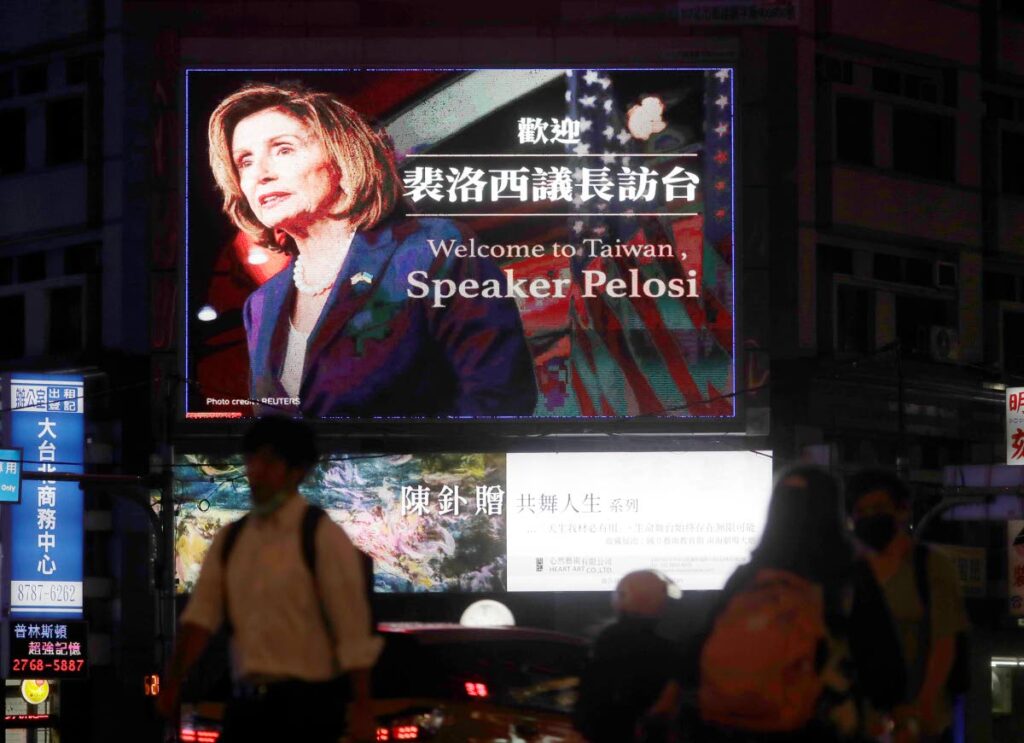 People walk past a billboard welcoming US House Speaker Nancy Pelosi, in Taipei, Taiwan, on August 2. - 