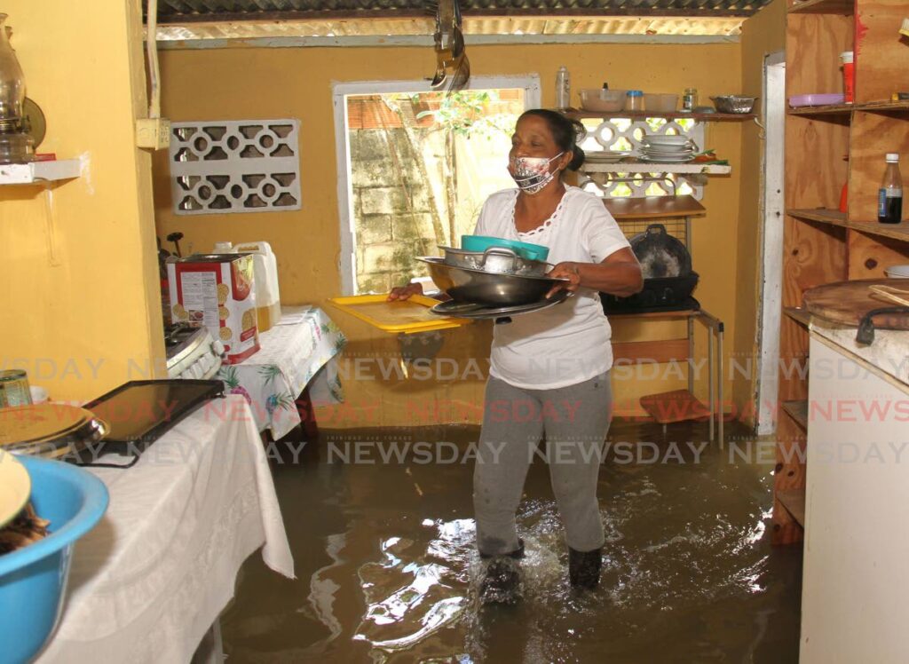 Korisha Latiff moves some of her kitchen utensils to higher ground after her Caroni Village, Caroni home was flooded on Friday. - Photo by Ayanna Kinsale