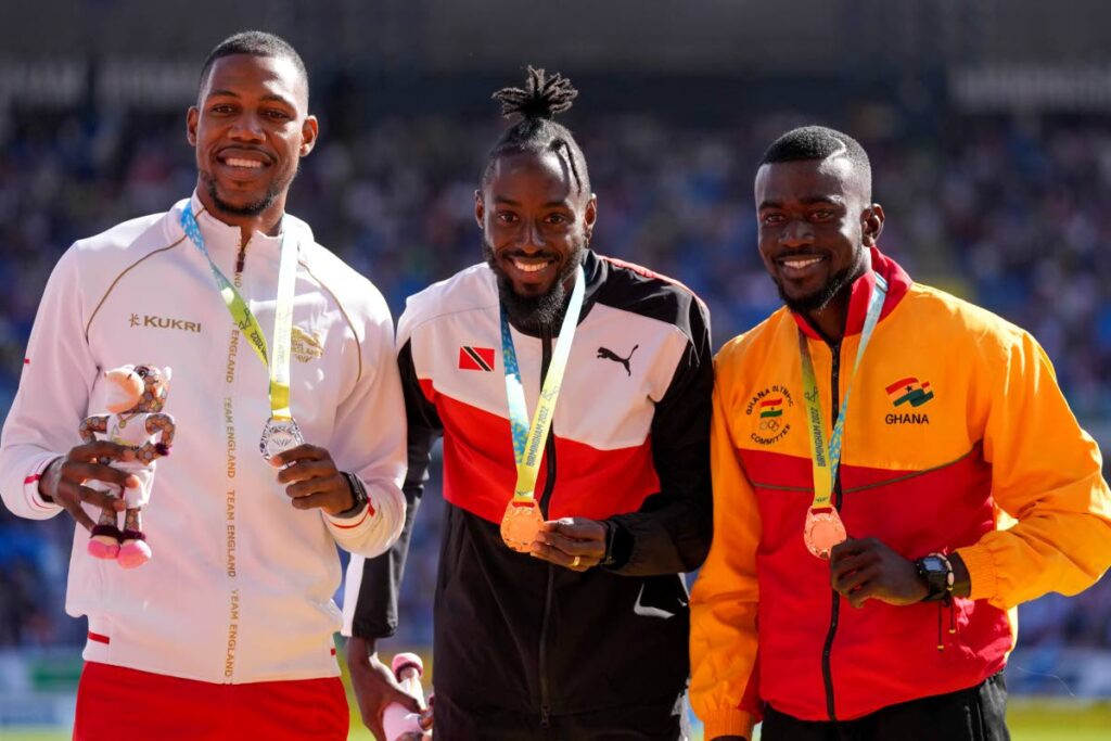 Men's 200 metres gold medallist Jerome Richards, centre, of Trinidad and Tobago, stands with silver medallist Zharnel Hughes of England, left, and bronze medallist Joseph Paul Amoah of Ghana on the podium, in the Alexander Stadium at the Commonwealth Games in Birmingham, England, on Sunday. (AP PHOTO) 