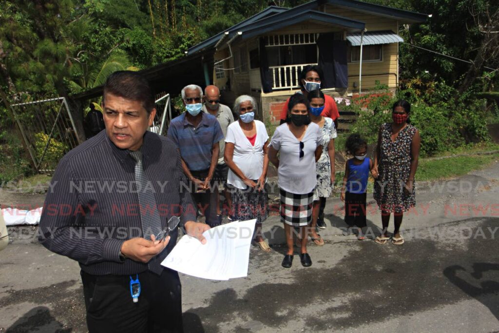 Attorney Prakash Ramadhar, left, speaks on behalf of the Narine family outside their Pluck Road, San Francique home at risk of collapse owing to a land slip. - File photo