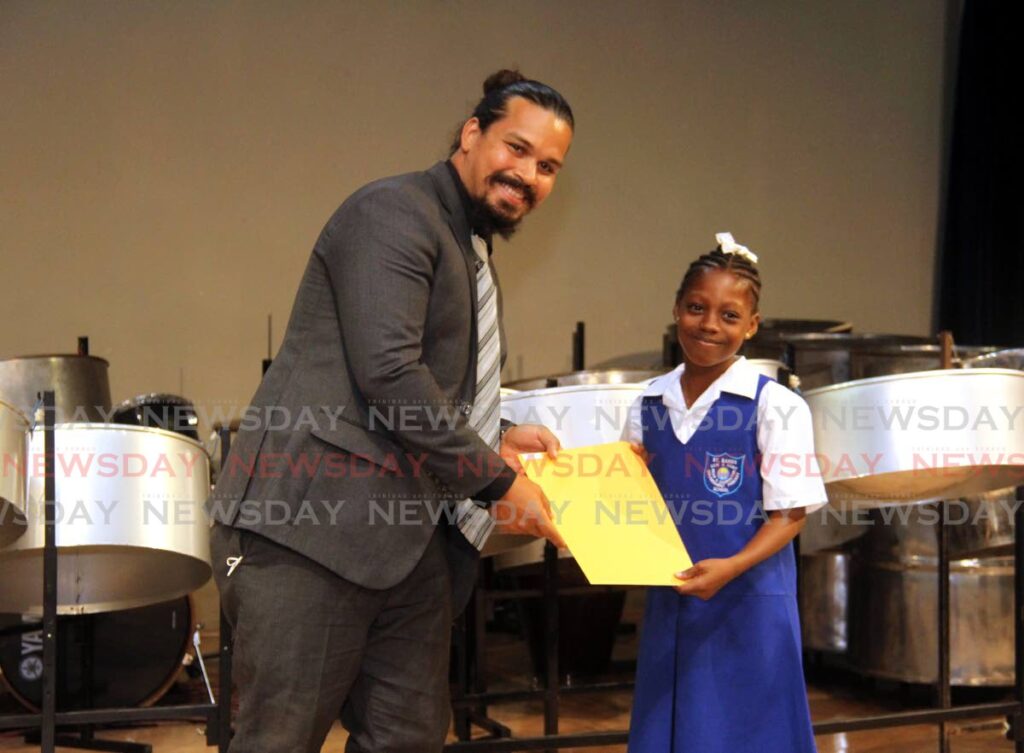 Club co-ordinator Seth Escalante presents Mikita Ragis of St Barbs Government Primary School with her prize for best vocalist in her camp during the Laventille Morvant School Improvement Project vacation music camp graduation at the Government Campus Plaza, Port of Spain.  Photo by Ayanna Kinsale