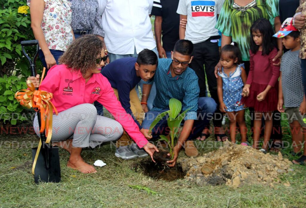 St Augustine MP Khadijah Ameen (left) is helped by little Rishaan Hosein and Councillor Richard Rampersad to plant a coconut tree at the Helping Hands Recreation Ground, Streatham Lodge Road  Extension, St Augustine on Thursday. Photo by Sureash Cholai