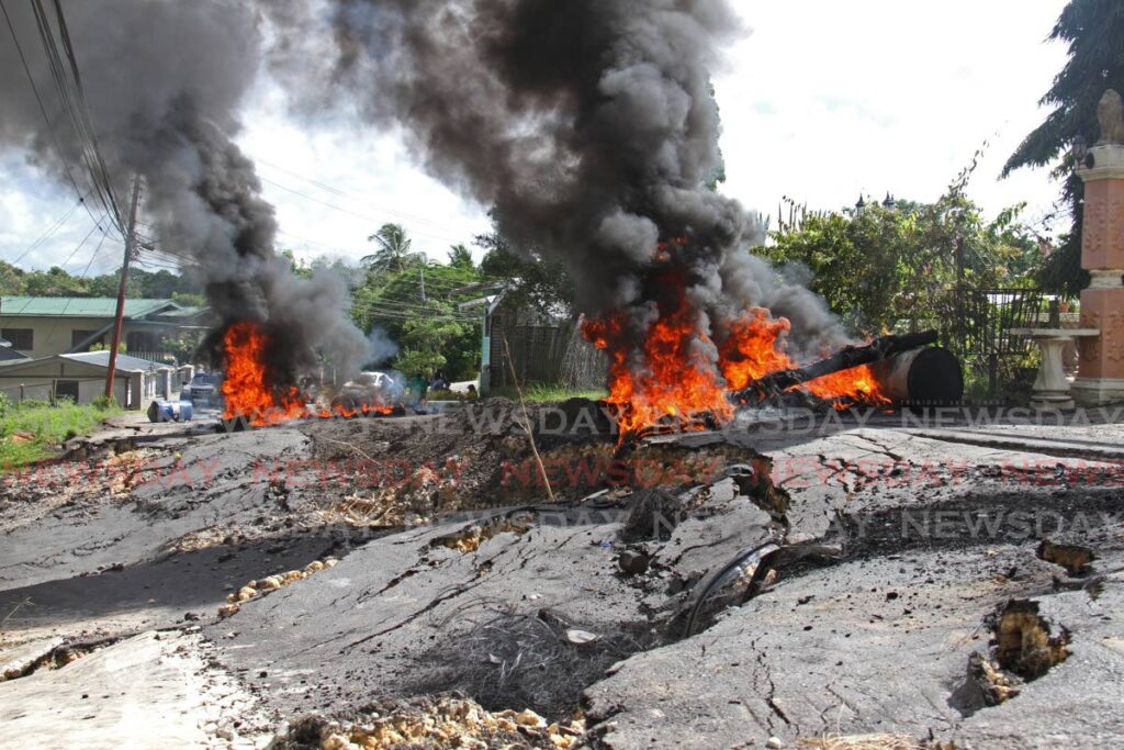 Residents of Papourie Road, Upper Barrackpore, burn debris on Thursday morning to protest the condition of the road. - MARVIN HAMILTON