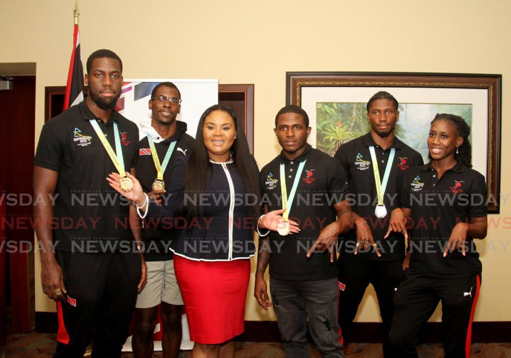 TT athletes Kashief King (left), Dwight St Hillaire (second from left), Che Lara (third from right), Jerod Elcock (second from right) and Mauricia Prieto (right), are joined in photo by Sports Minister Shamfa Cudjoe at the VIP Lounge, Piarco International Airport on Thursday, upon their return from the Commonwealth Games in Birmingham, England. - AYANNA KINSALE