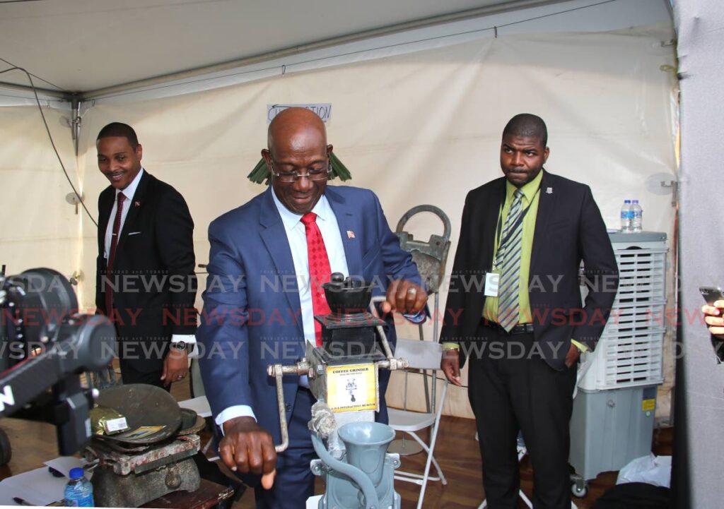 Prime Minister Dr Keith Rowley operates a coffee grinder on display the the Agri-Investment Forum and Expo at Queen's Park Savannah, Port of Spain on Friday. - SUREASH CHOLAI