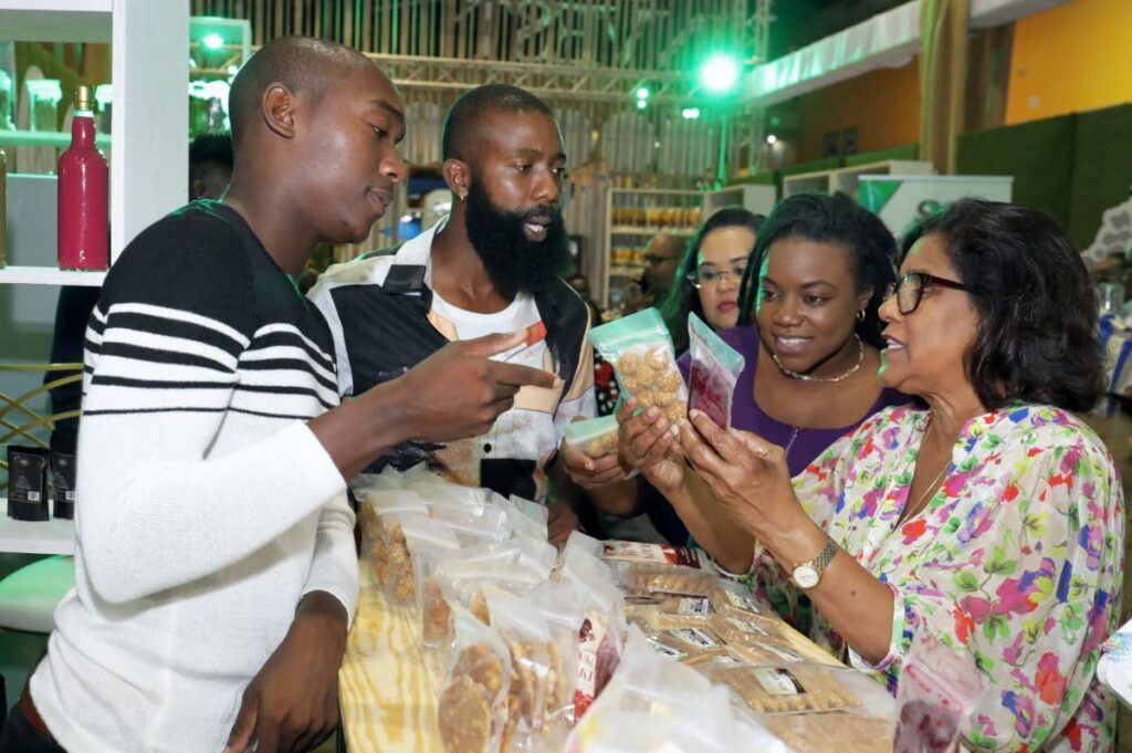 Tom Tom's Akimola Prince, second from left, and Ornaldo Lindow talk about their products with Trade and Industry Minister Paula Gopee-Scoon at the TIC in Tobago.  Photo courtesy THA