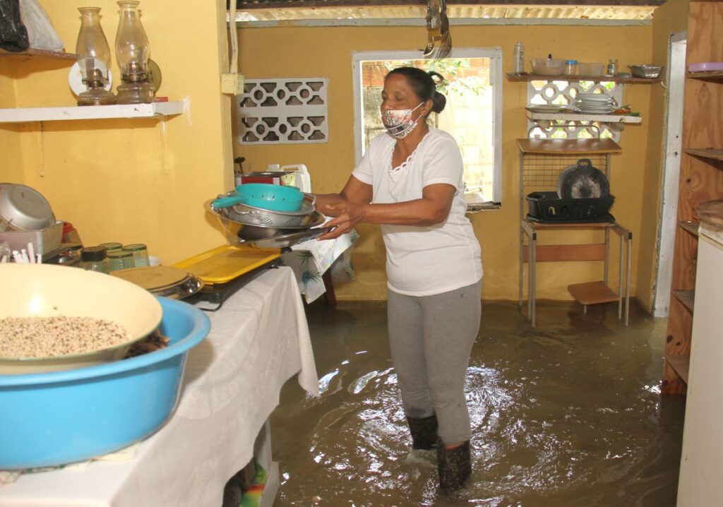 Korisha Latiff walks with her utensils after her Caroni Village, Caroni home was flooded out last month. - AYANNA KINSALE