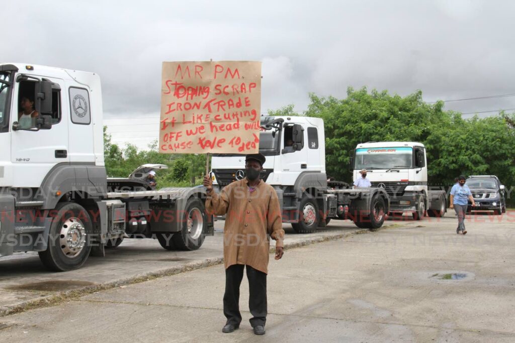 A man holds a sign in protest against the six-month scrap iron ban during a motorcade from San Fernando to Port of Spain in August. - MARVIN HAMILTON