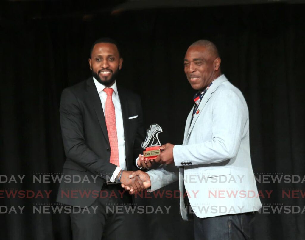 Sprinter Richard Thompson, left, being inducted in the Hall of Fame presented by Tobago House of Assembly Assemblyman Wane Clark during the launch of the Secondary Schools Track and Field season at the Central Bank Auditorium in Port of Spain, on Tuesday. - SUREASH CHOLAI