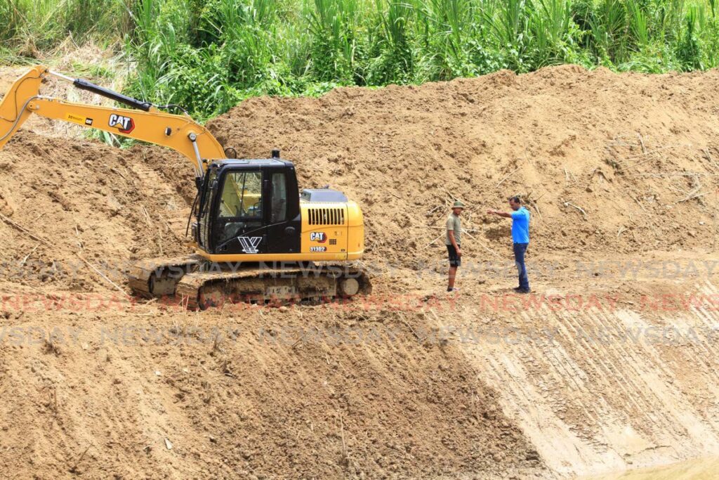 A backhoe operator receives instructions before performing restoration works on the Caroni River bank at Ibis Gardens, Caroni on Tuesday. - Angelo Marcelle