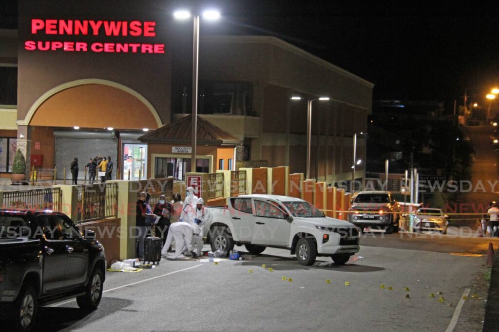 Police and crime scene investigators process the crime scene of a murder and attempted robbery at Pennywise Plaza, La Romain. Photo by Marvin Hamilton