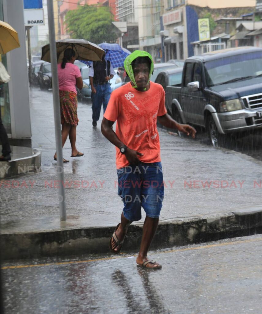 A man hurrys through heavy rain on Frederick Street, Port of Spain on Tuesday. - SUREASH CHOLAI