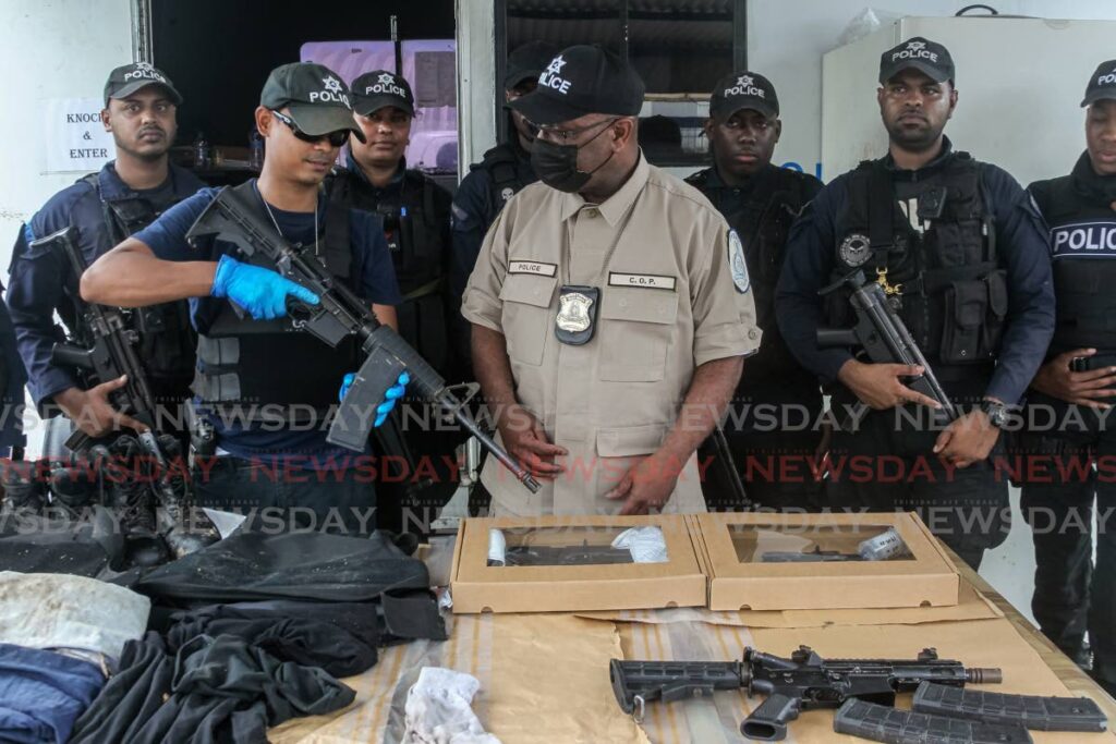 Constable Arvin Boodram shows Acting Police Commissioner McDonald Jacob one of the AR15 assault rifles used by the bandits in Tuesday’s failed Pennywise robbery. The weapons were displayed on Wednesday 
at the La Romaine Police Post. Photo by Roger Jacob