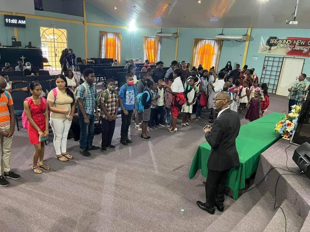 Rev Albert Gray of the Arouca Pentecostal Church speaks to parents and students at the church's distribution of school supplies. - 
