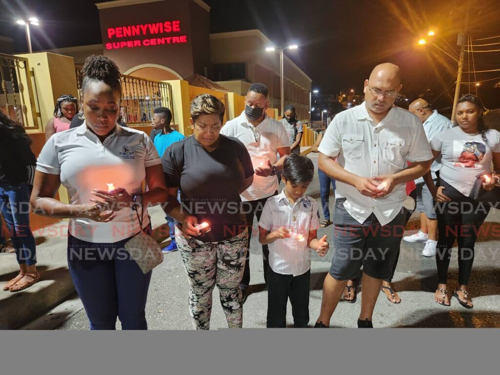 Relatives and colleagues of slain security officer Jeffery Peters, joined relatives of slain Jerry Stuart and wounded Peola Baptiste in prayer during a candlelight vigil on Saturday at the site where the tragedy occurred at Pennywise Super Centre, La Romaine. - Photo by Yvonne Webb