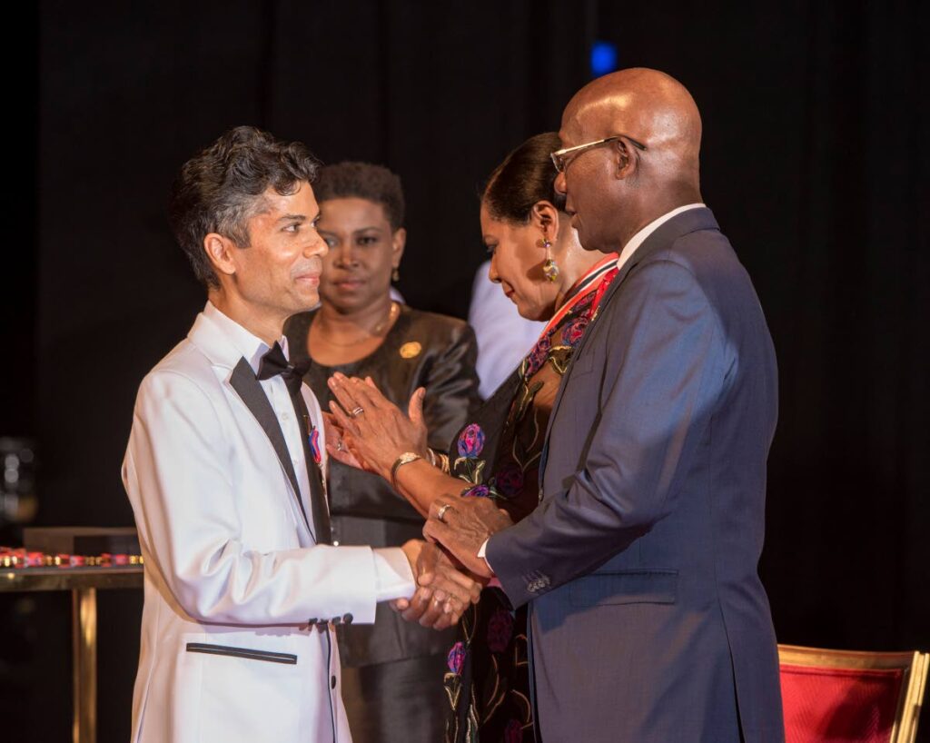 UWI lecturer Dr Jerome Teelucksingh is congratulated by Prime Minister Dr Keith Rowley after receiving his national award from President Paula-Mae Weekes at NAPA on September 24. - Photo courtesy Office of the President