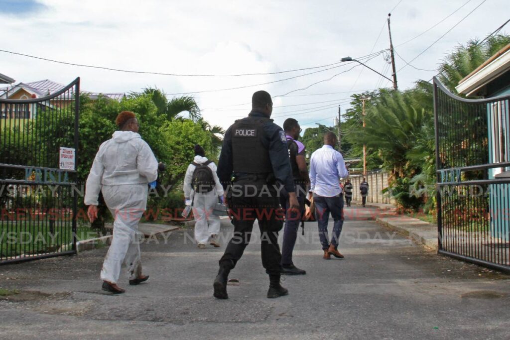 CRIME SCENE: Policemen and crime scene investigators enter the Krista Park gate community in Mayaro on Monday after other police officers shot dead four bandits who were caught at a house in the compound. Photo by Marvin Hamilton