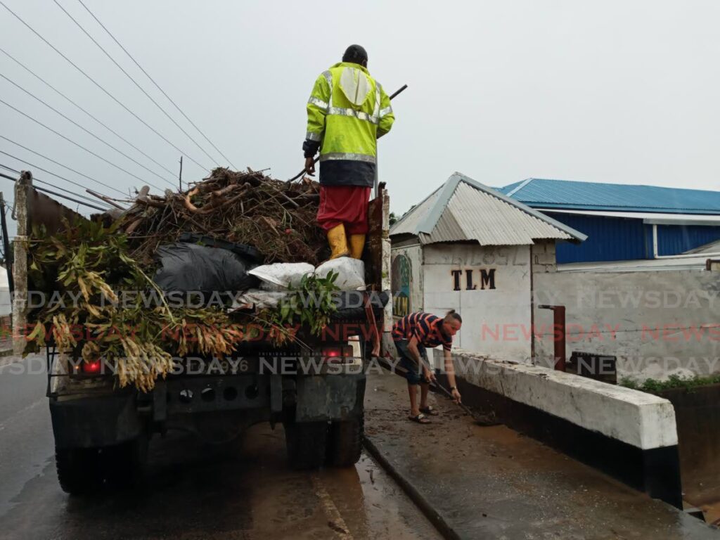 Tunapuna/Piarco Regional Corporation employees, conduct clean up exercises on the Eastern Main Road in Arouca on Thursday after floods. - Photo by Angelo Marcelle