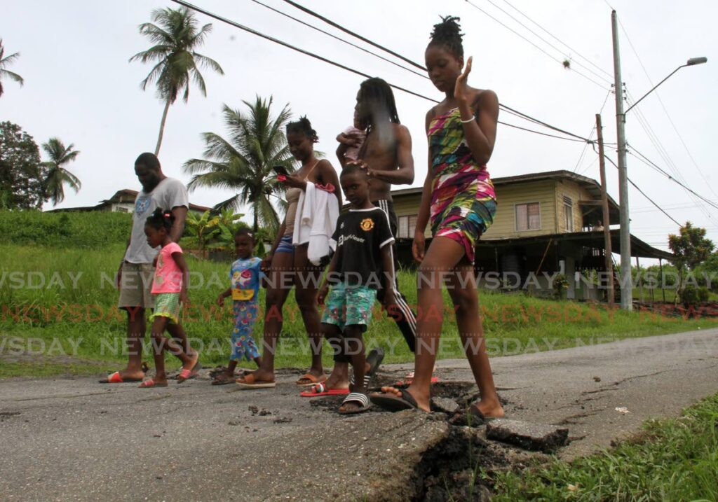 Residents walk over a crack in the road caused by land movement at Skinner Trace, Quarry Village, Siparia. - Photo by Ayanna Kinsale 