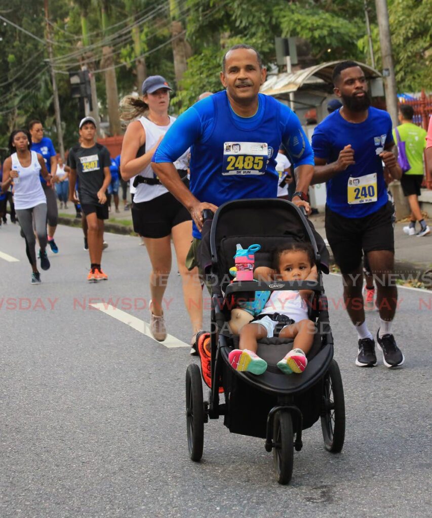 A runner with a child, in a stroller, during Sunday's RBC Race for the Kids around the Queen's Park Savannah, Port of Spain.  Photo by Sureash Cholai