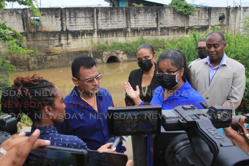 Works and Transport Minister Rohan Sinanan, left, and Director of Drainage Katherine Badloo-Doerga  with other officials from his ministry speaking about the stolen flap gate behind them. - SUREASH CHOLAI