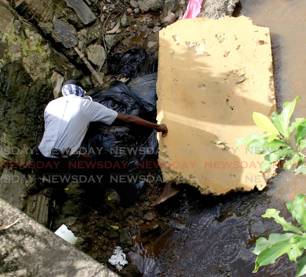 GRUESOME FIND: An officer looks at the dismembered human leg found under a piece of foam in a shallow stream in Cunupia on Monday. PHOTO BY SUREASH CHOLAI - 