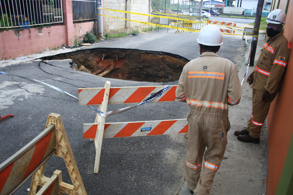 A T&TEC crew examine one of the three sinkholes in Beetham Gardens, caused by a suspected collapsed sewer main. Photo by Suresh Cholai 