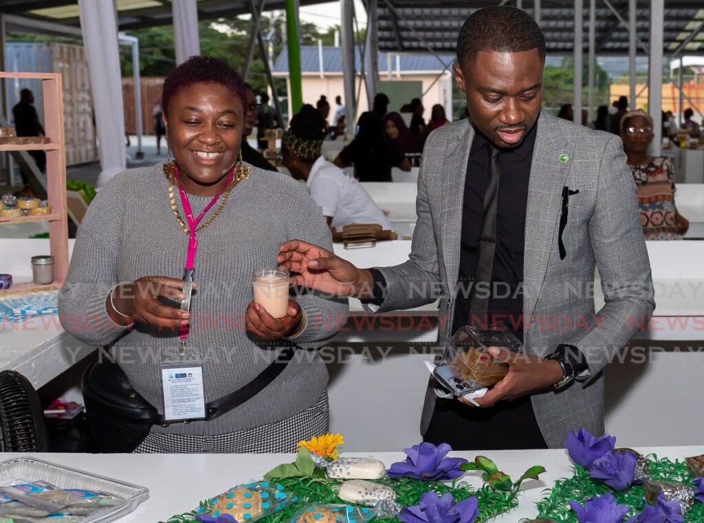 Chief Secretary Farley Augustine, right, buys a scented candle from Melissa Sylvan, left, of Exotic Bath Creations by Mel at the opening of Shaw Park Food Hub on Monday. Photo by David Reid
