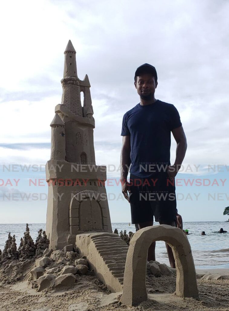 Jamal Job stands next  to his 5 feet 9 inches sandcastle sculpture that was created at Las Cuevas on October 15, 2022. Photo by Elexzine Bissoo