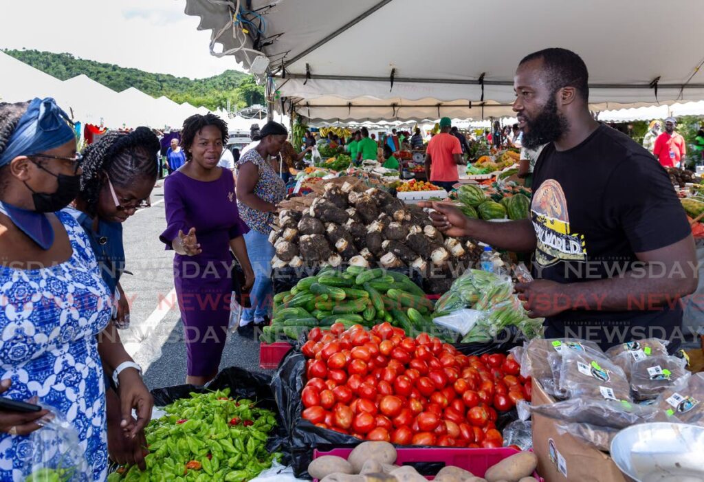 Mason Hall farmer Anderson Duncan, right, sells his produce at World Food Day, Parade Ground, Bacolet, Wednesday. Photo by David Reid