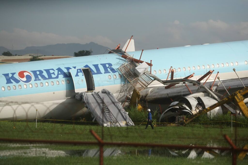 In this file photo, a man walks beside a damaged Korean Air plane after it overshot the runway at the Mactan-Cebu International Airport in Cebu, central Philippines on October 24.  (AP PHOTO)