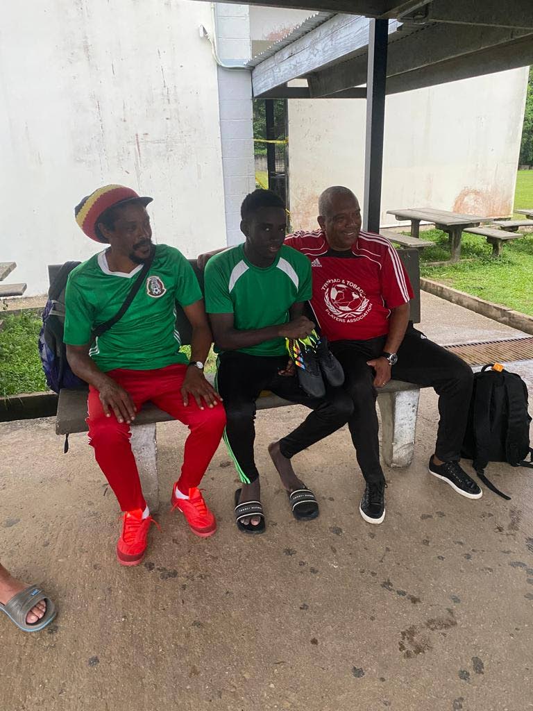 San Juan North Secondary School football captain Larry Noel, middle, receives a new pair of boots for his goal scoring season from football enthusiast Earl 