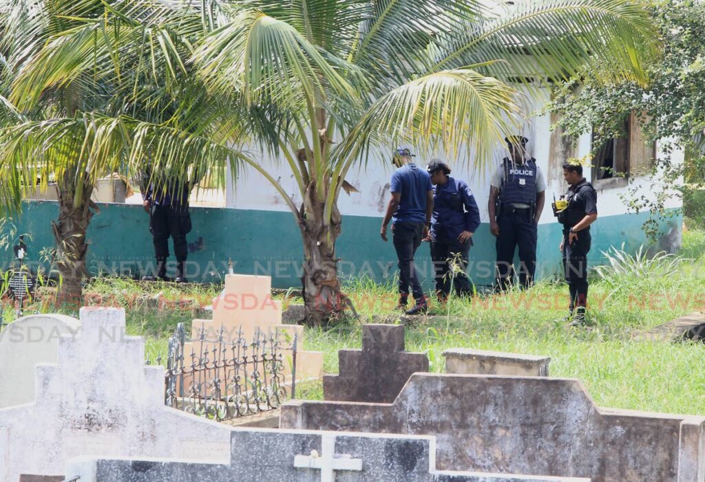 Police search for clues at the Tunapuna public cemetery the scene of a double murder on Saturday.  - ROGER JACOB