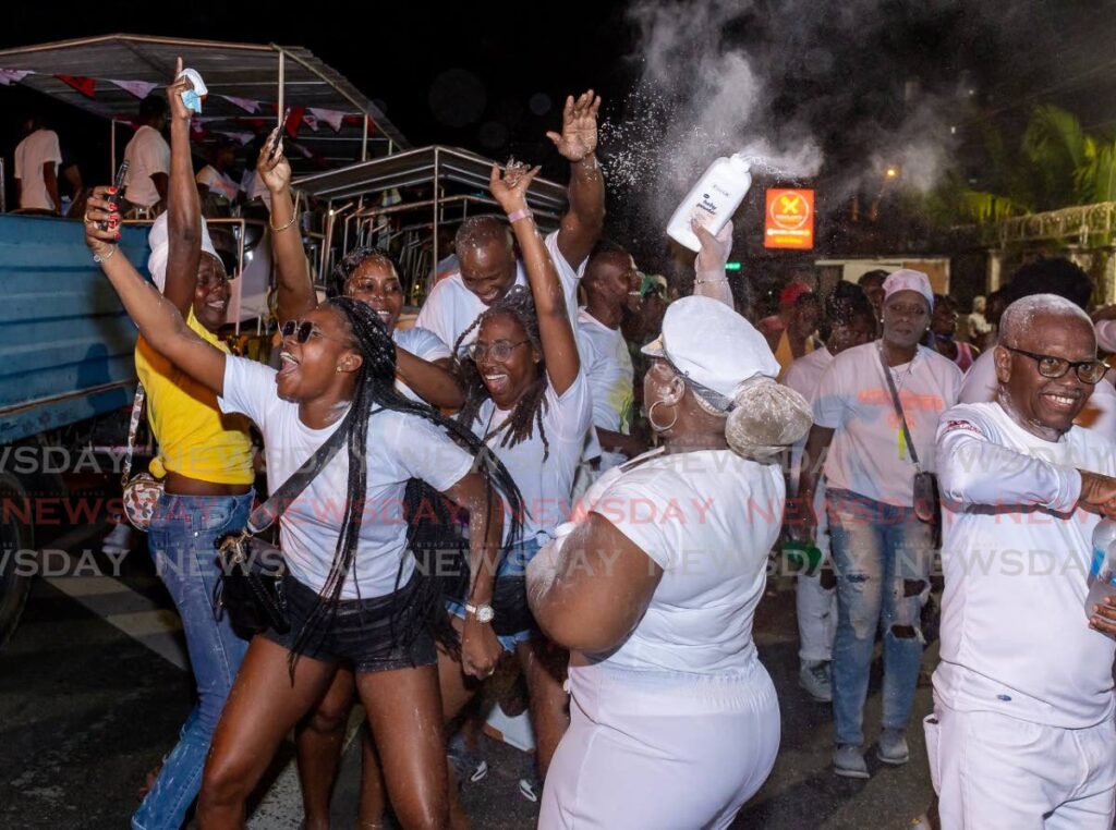 Masqueraders spray each other with powder at the Pan and Powder parade through the streets of Scarborough on Friday night. - David Reid